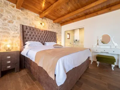 a bedroom with a large bed with a stone wall at Harmonia Bungalows & Pool in Sveti Stefan