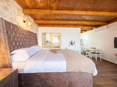 a bedroom with a large bed with a stone wall at Harmonia Bungalows & Pool in Sveti Stefan