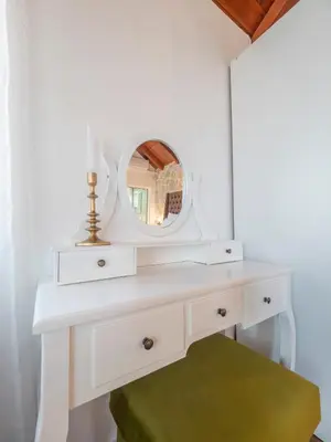 a dressing table with a mirror and a green ottoman at Harmonia Bungalows & Pool in Sveti Stefan