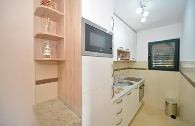 a kitchen with a white refrigerator and a tv at Promenade,5 min Old Town in Kotor