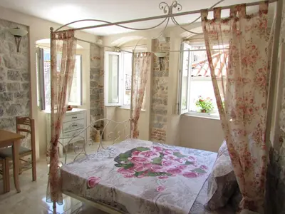 a bedroom with a canopy bed with flowers on it at Apartments Popovic in Kotor