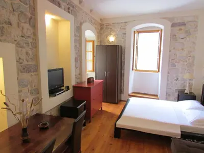 a bedroom with a bed and a dresser and a television at Apartments Popovic in Kotor