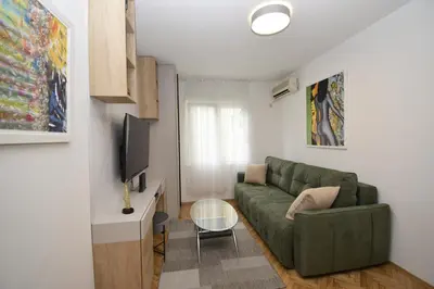 a living room with a green couch and a television at Studio apartment Art Zone in Podgorica