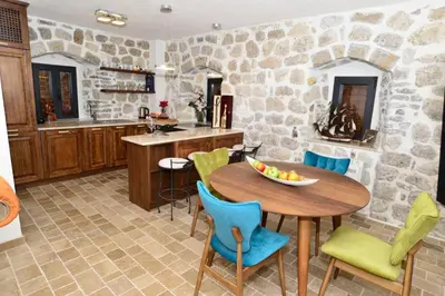 a kitchen with a table and chairs and a stone wall at Waterfront Villa in Muo in Kotor