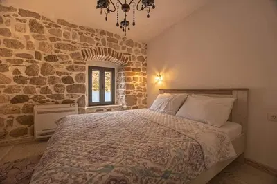 a bedroom with a bed and a stone wall at Waterfront Villa in Muo in Kotor