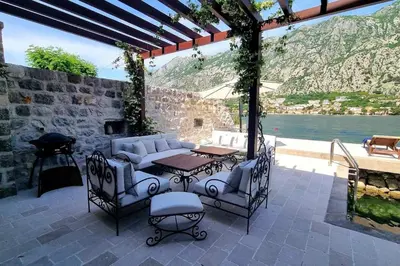 a patio with a table and chairs and a table and a grill at Waterfront Villa in Muo in Kotor