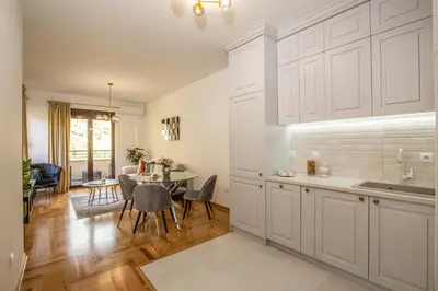 a kitchen with white cabinets and a table with chairs at Apartment Poetica Del Mare, Budva, Bečići in Becici
