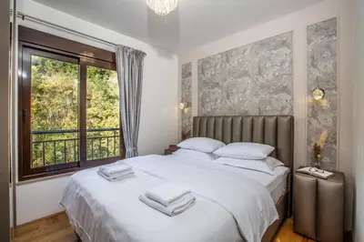 a bedroom with a bed with white sheets and a window at Apartment Poetica Del Mare, Budva, Bečići in Becici