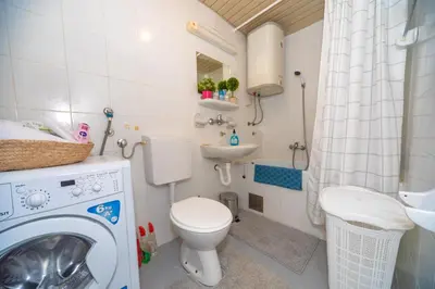 a small bathroom with a washing machine and a sink at Aloha Apartman in Bar