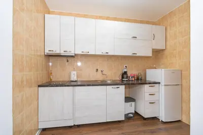 a kitchen with white cabinets and a white refrigerator at Aloha Apartman in Bar