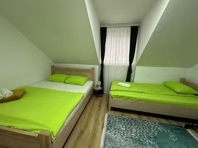 two beds in a room with green sheets and a window at Apartman Vucinic in Cetinje