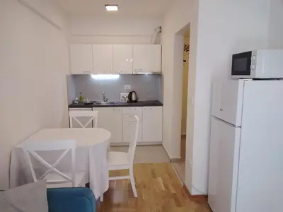 a small kitchen with a table and a white refrigerator at Yeshill Homes in Budva