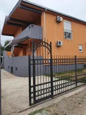 a building with a gate in front of a house at Apartmen Kuca za odmor i familiju in Bar