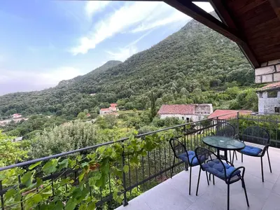 a balcony with a table and chairs and a mountain at Bed & Wine Djonovic in Virpazar
