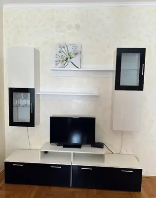 a living room with a tv and a white table at Просторная квартира в Петровце с видом на море in Petrovac na Moru
