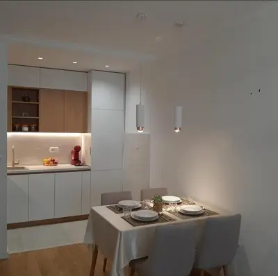 a dining room with a table with chairs and a kitchen at Apartment in Central Point in Podgorica