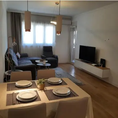 a living room with a table with chairs and a tv at Apartment in Central Point in Podgorica