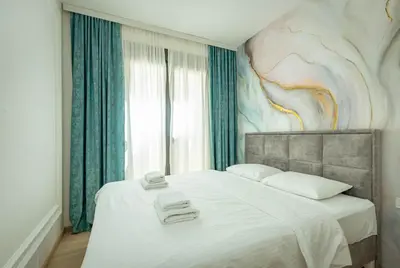 a bedroom with a large bed with a painting on the wall at Miracle apartment in Kotor