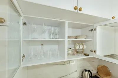a white cabinet filled with glasses and plates at Miracle apartment in Kotor