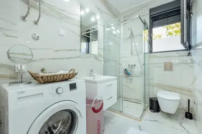 a white bathroom with a washing machine and a shower at Miracle apartment in Kotor