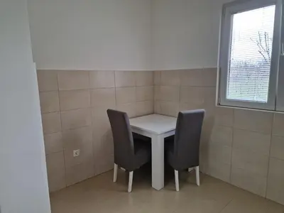 a small table with two chairs and a window at Apartman Tološi in Podgorica