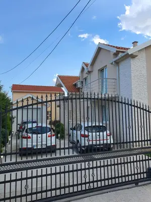 a black fence with cars parked in front of a house at Apartman Tološi in Podgorica