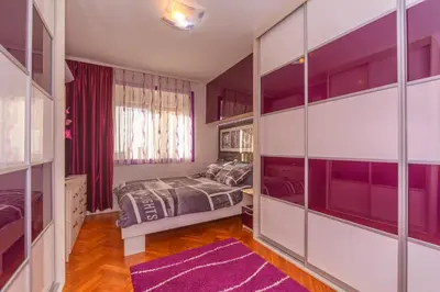 a bedroom with purple walls and a bed and a purple rug at Beni Apartment in Bar