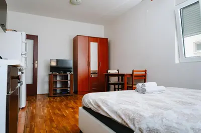 a bedroom with a bed and a desk and a television at Stex Urban 1 in Podgorica