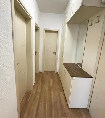 a hallway of an apartment with white cabinets and wood floors at El Pasaja in Dobra Voda
