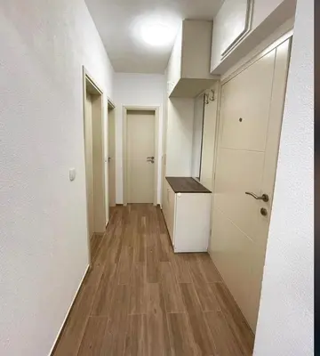 a hallway of an apartment with white walls and wooden floors at El Pasaja in Dobra Voda