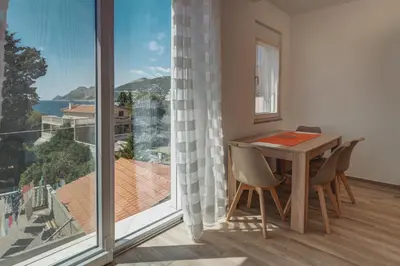 a dining room with a table and a large window at El Pasaja in Dobra Voda