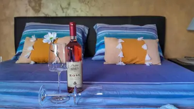 a bottle of wine and a glass on a table in front of a bed at Sea view apartment in Kotor ! Apartment Popica in Kotor