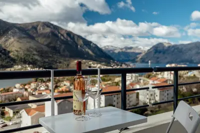 a bottle of wine and two glasses on a table at LANA Sea View Apartment in Kotor