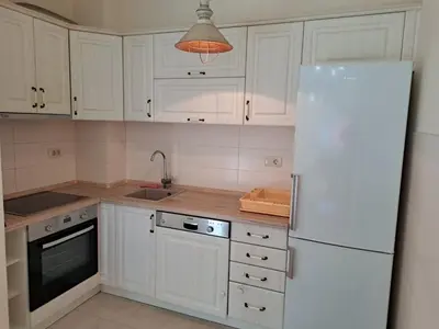 a kitchen with white cabinets and a white refrigerator at Delta apartment City kvart in Podgorica