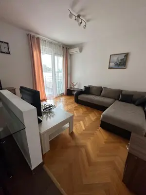 a living room with a couch and a desk with a computer at Vanilla Apartment Petrovac in Petrovac na Moru