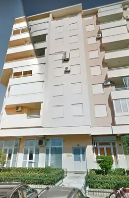 a tall white building with cars parked in front of it at Norandvik Apartment in Podgorica