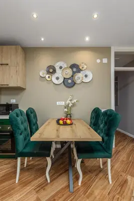a dining room table with green chairs and plates on the wall at XIO Apartments in Bar