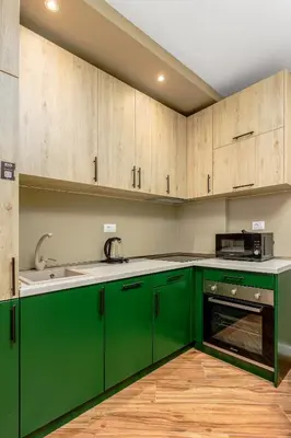 a green kitchen with wooden cabinets and a sink at XIO Apartments in Bar