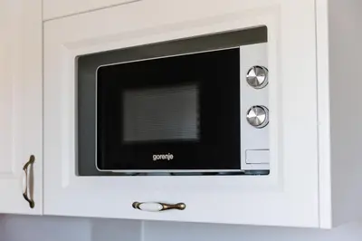 a microwave oven sitting inside of a white cabinet at XIO Apartments in Bar