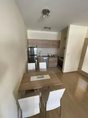 a kitchen with a wooden table and white chairs at Apartment CK in Podgorica