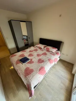 a bedroom with a bed with a blanket and a mirror at Apartment CK in Podgorica