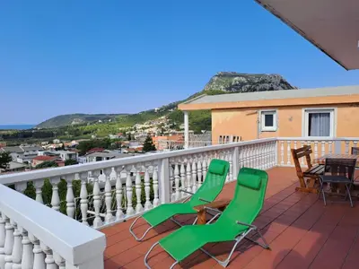 a balcony with two green chairs and a table at Villa Peonia in Sutomore