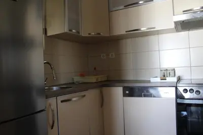 a small kitchen with white cabinets and a sink at Honey Home in Podgorica