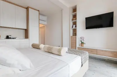 a white bedroom with a bed and a flat screen tv at Viewpoint Villa in Budva