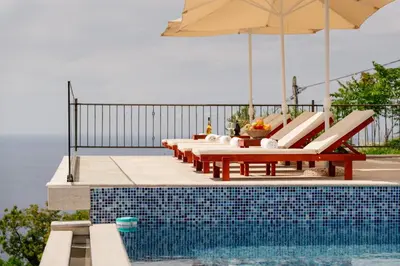 a row of chairs and an umbrella next to a pool at Viewpoint Villa in Budva