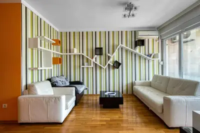 a living room with two white couches and a striped wall at Studio apartment in the centre of Budva in Budva