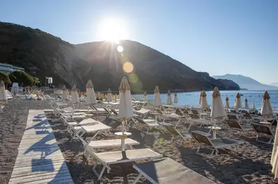 a group of chairs and umbrellas on a beach at Studio apartment in the centre of Budva in Budva