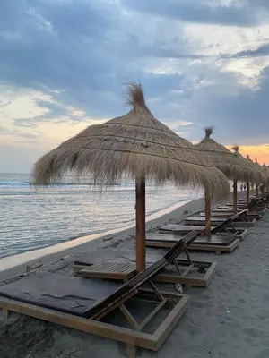 a row of beach chairs with umbrellas on a beach at Crown Apartment in Ulcinj