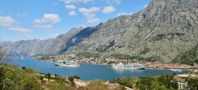 two boats are docked in a bay with mountains at Huge Apartment with Stunning View and Sauna in Kotor