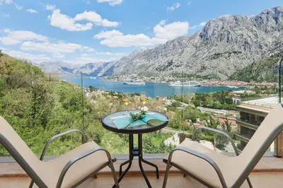 two chairs and a table on a balcony with a view of a lake at Huge Apartment with Stunning View and Sauna in Kotor